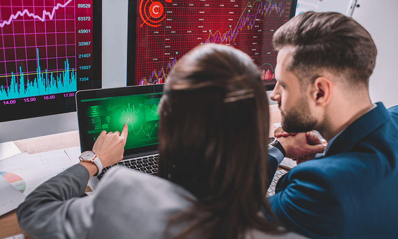 A pair of analysts seated in front of a laptop, reviewing data together.